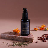 Cannacomplex™ Nourishing Face Serum is a face oil serum placed on a marble surface with an Rosehip plant next to it.