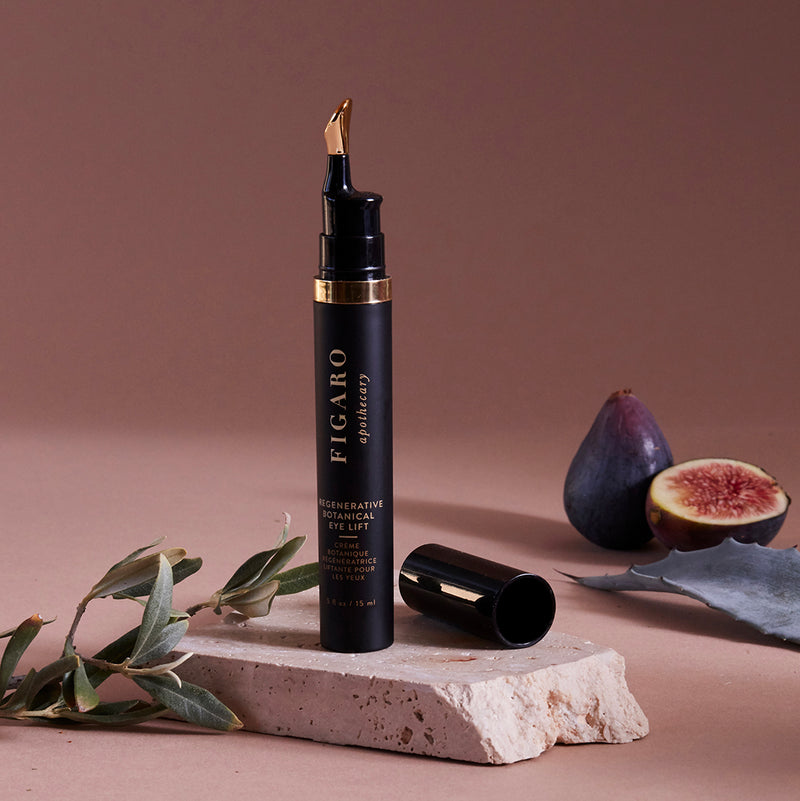 Regenerative Botanical Eye Lift is an eye contour cream placed on a marble surface with an Agave leaf and figs next to it.